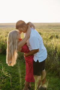 A person dipping their partner in a field as they are about to kiss