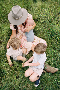 Photo from above of a mom with her 3 kids sitting in the grass