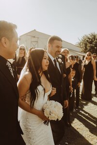 a bride walking down the aisle with two men in suits next to her