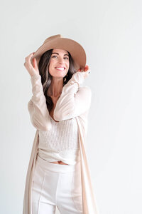 Jen Pike holding the brim of her tan hat with both hands for creative photography session.