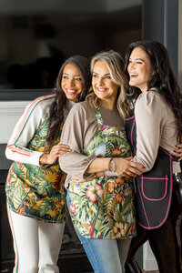 three women wearing athena stirs aprons