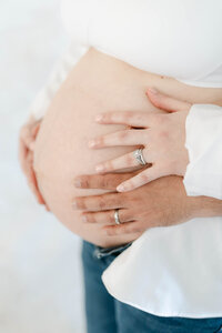 Mother with white dress holds baby, reflection in the mirror of their nursery