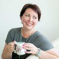 Profile photo of Lucy Kelly  smiling and holding a coffee mug