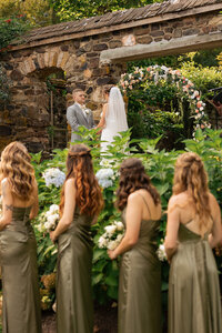 Bridemaids looking at the bride and groom during their rustic wedding ceremony in  Parque Ridley Creek in Peensly