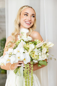 Close-up portrait of a gorgeous bride as she smiles brightly while holding her bouquet. 