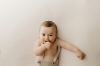 Cute baby with a curious expression wearing overalls during a Mullingar photoshoot