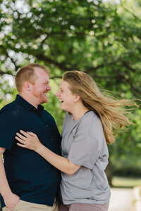 A couple laughing as they have their arms around each other 