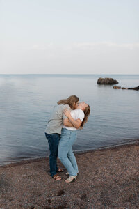 A couple hugging on a beach while laughing 