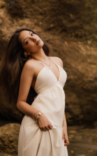 girl in white dress halter style with her had back, no smile, long dark hair posing for her senior portraits in los angeles