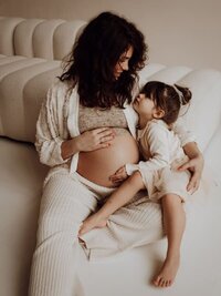Intieme blikken tussen zwangere mama en dochter tijdens zwangerschapsshoot te Beveren-Waas