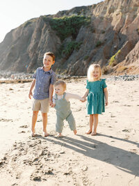three siblings playing on the sand at dana point beach family mini session