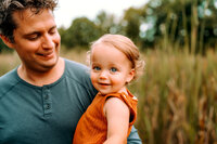 Father looks at toddler who is looking at the camera