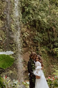 bride and groom in a jungle near a waterfall