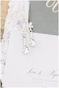 Details of wedding earrings styled over vow books