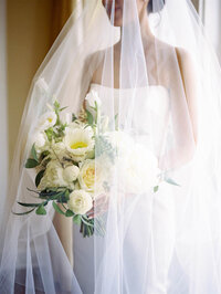 Bride holding bouquet under veil