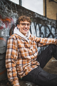 Ethan iliff posing near the highline and the river by a concrete graffiti wall for his senior photos pittsburgh session shot by his mother Heidi iliff.