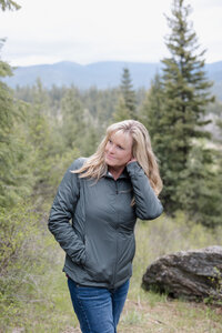 Female photographer in the mountains with hand under hair.