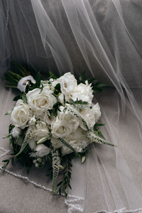 White wedding bouquet sitting atop a wedding veil | Emma LeeAnn Photography