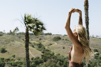 Aine Rock outside with her arms above her head 