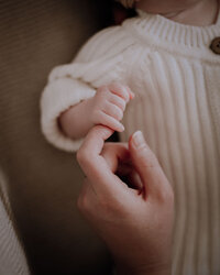 Mother holds daughter in her arms while they snuggle together, bumping noses