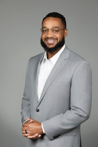 male headshot in detroit studio wearing a  gray suit on a gray backdrop
