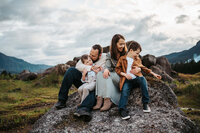 Parents and their two boys  sitting on a rock in the Columbia river gorge