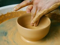 person creating pottery on a wheel