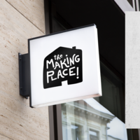 A sign with a black logo of a cute house silhouette with the words "the making place!" written over top in playfully hand drawn typography