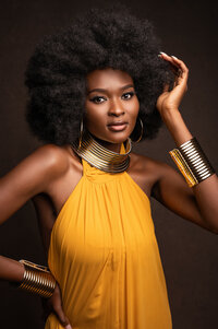 A stunning portrait of a woman of color with a voluminous afro, wearing a vibrant yellow dress and gold jewelry. Captured in a magazine-worthy style by Leslie Q Photography, this image exudes confidence and elegance.