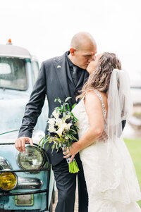 Couple stands in front of a vintage car sharing a kiss after their wedding in Dallas Fort Worth. Taken by Danni Lea Photography DFW Wedding Photographer