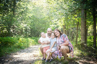 family sitting in amongst a tree lined path  photo by Jessica Stewardson