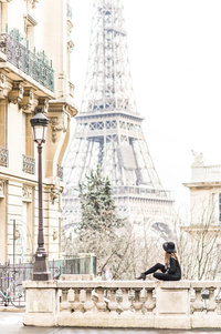 Stephanie Messick sitting on railing in front of the Eiffel Towner.