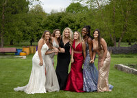 Six senior friends in prom dresses holding hands and smiling.