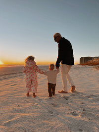 dad walking on the beach with his little girls