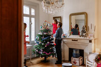 A little girl in her dad's arm decorating the Christmas tree