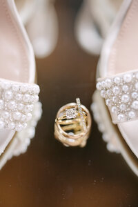 A detailed shot of a beautiful diamond wedding ring framed in between shoes.