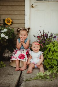 two kids sitting next to plants