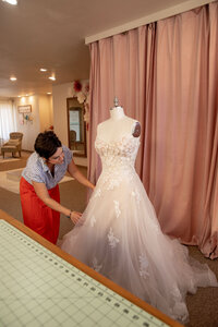 A seamstress adjusting a wedding gown on a mannequin