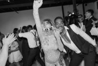 A bride cheers in her reception party outfit.