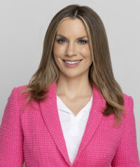 woman with long straight blonde hair wearing a bright pink blazer