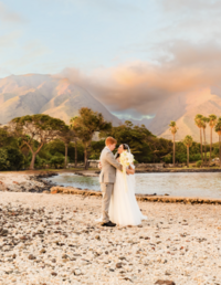 bride and groom posing in front of west maui mountains at sunset for their olowalu plantation house on maui photographed by love and water