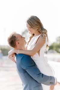 Photo of groom holding bride up while they both smile at each other taken by Coastal Maine wedding photographer