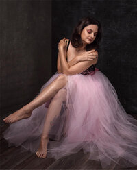 woman in a baby pink tulle sitting with crossed arms and pointed crossed legs