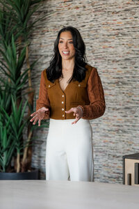A women standing, engaged in a conversation about sales techniques, with a plant nearby.