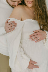 close up of pregnant women standing in front of man with hands on her belly knoxville tennessee newborn photographer