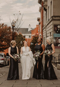 A newlywed walking down a sidewalk with their wedding party 