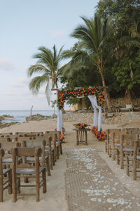 A luxurious beachfront wedding ceremony in Mexico, where chic seating and fine art floral arrangements create a romantic aisle experience.