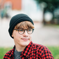 Teenage boy with glasses and a beanie and red plaid shirt