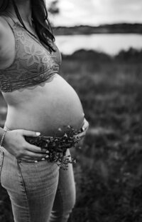 black and white photo of  a pregnant woman wearing jeans and a lace bralette