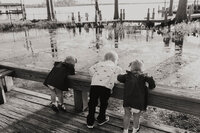 A photo of three little children looking over the ledge into the water